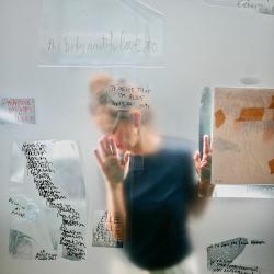 Christine Herzer, derrière une vitre où sont inscrits des mots