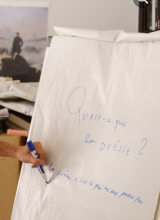 Photo d'une main écrivant sur un tableau, Qu'est-ce que la Poésie ?